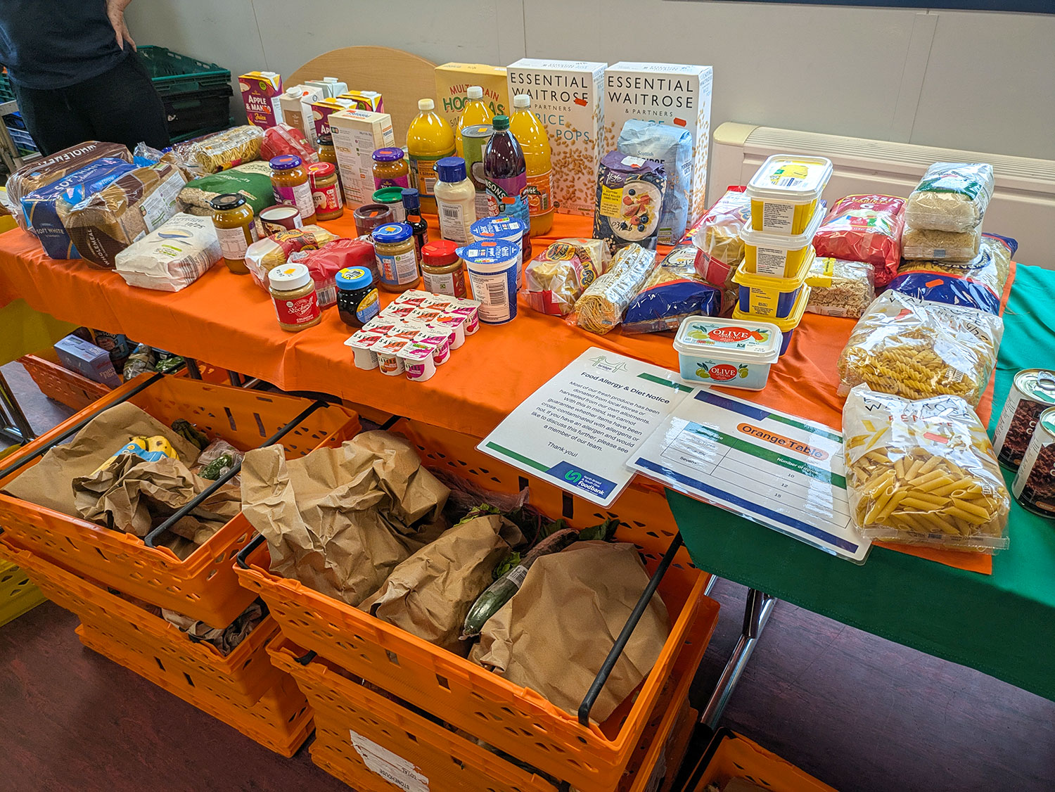 Bags and boxes of food on a long table, ready for members of the Bridge food club