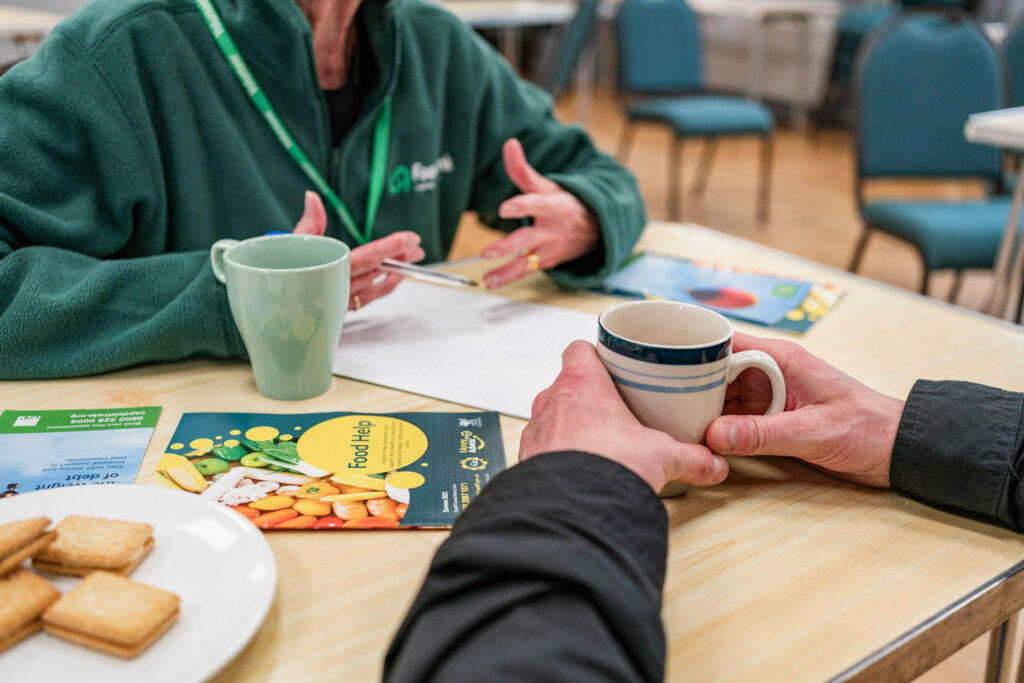 A support worker sitting at a table with a client, giving advice and tea