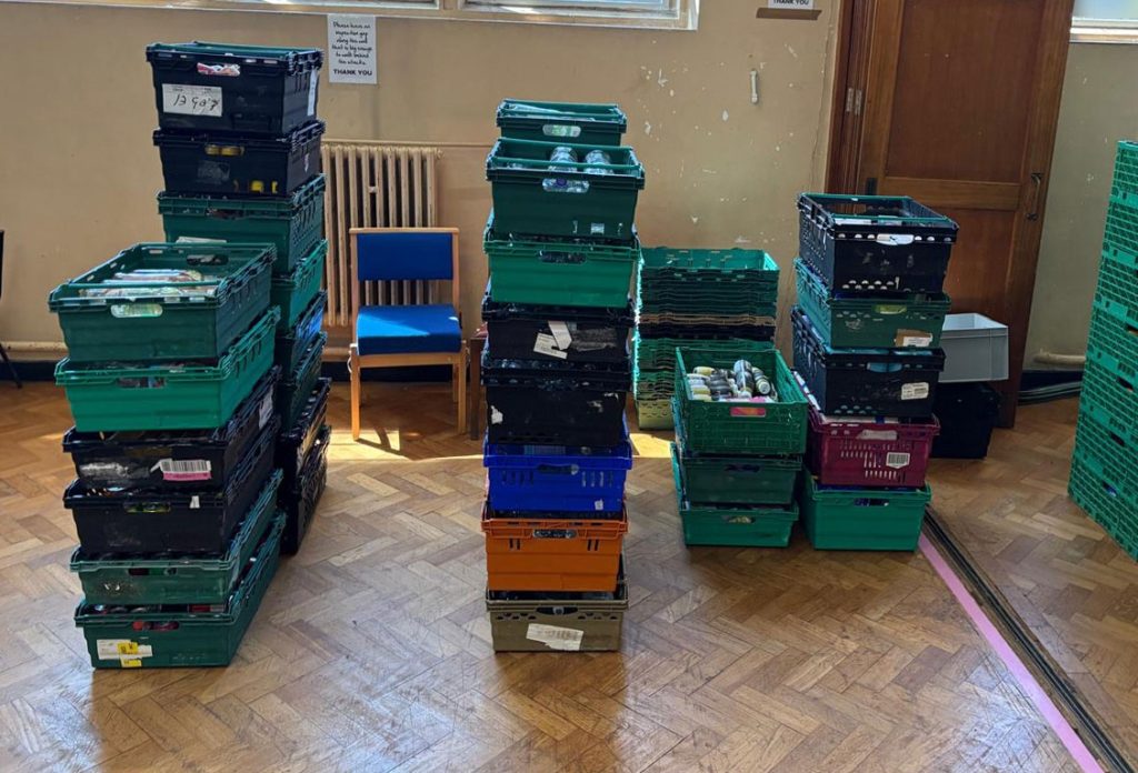 warehouse crates Stacked green plastic crates containing food items are arranged on a parquet floor in a warehouse-like space.